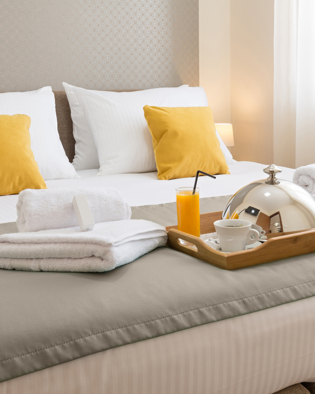 A freshly made bed with crisp white linens, folded towels and a breakfast tray — showing the hotel-standard finish NFS Management delivers